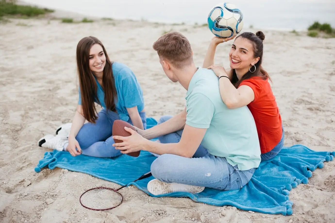 Ganzaufnahme glücklicher Freunde, die am Strand sitzen